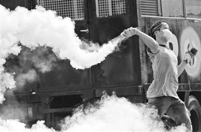 12月2日，泰國(guó)曼谷，一名反政府示威者在總理府附近向負(fù)責(zé)執(zhí)勤的警察投擲催淚彈。英拉請(qǐng)求示威者不要再試圖占領(lǐng)政府工作部門，不要逼迫政府工作人員選邊站。