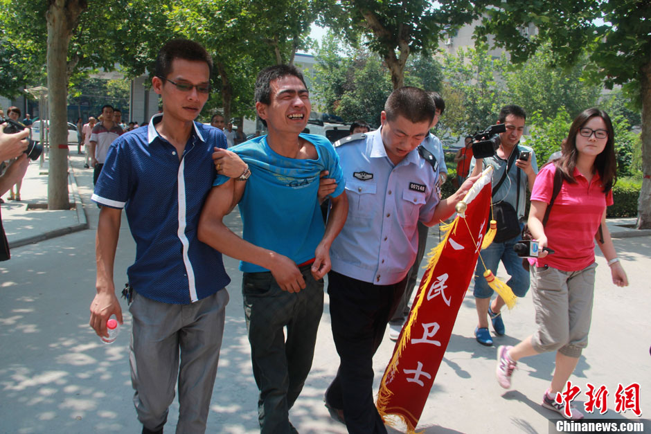 圖為獲救嬰兒父親情緒一度失控，當(dāng)?shù)鼐焦ぷ魅藛T對(duì)其進(jìn)行攙扶。張一辰 攝