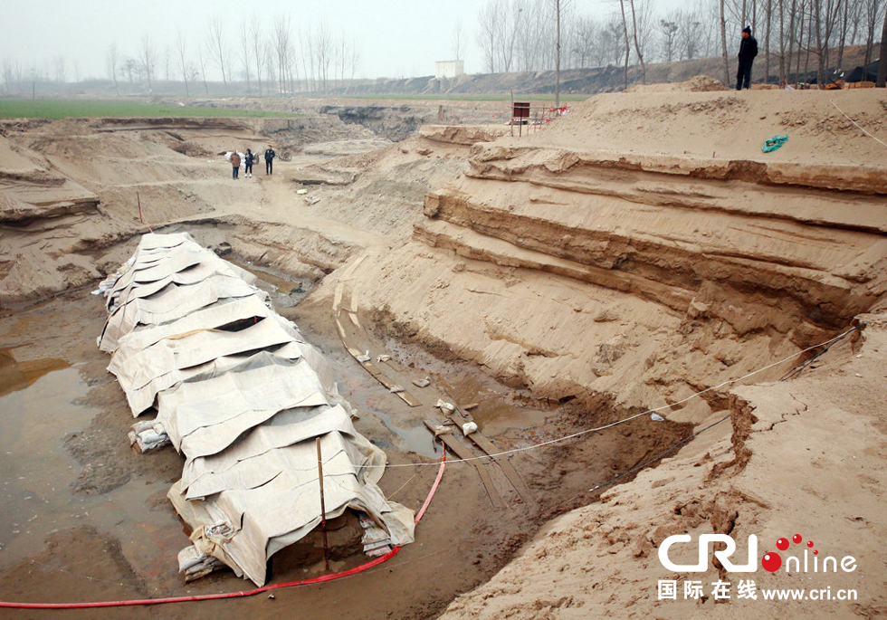 2014年1月6日，河南洛陽古沉船發(fā)掘現(xiàn)場，近日有雨雪天，考古人員給古沉船披上一層“雨衣”。