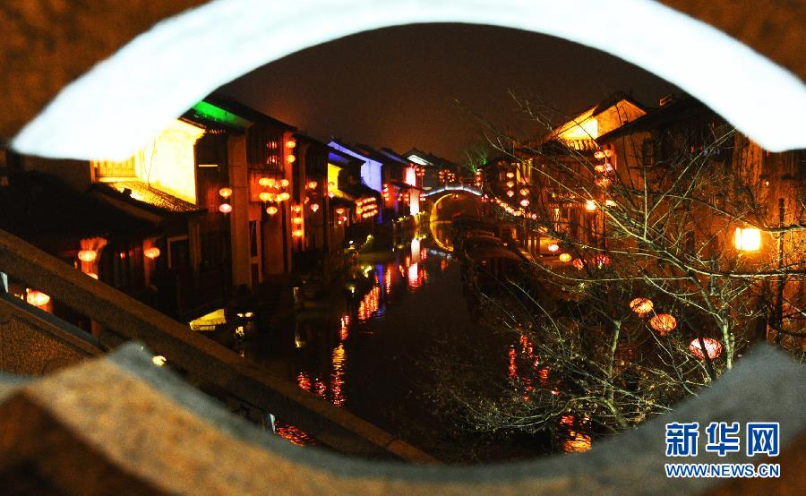 1月30日透過(guò)蘇州市新民橋孔拍攝的山塘古街水巷夜景。
