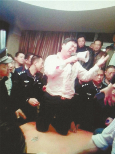 　4月19日，泰州市濱江工業(yè)園區(qū)管委會招待中心，一男子跪在酒桌上喊話求饒。李根 攝