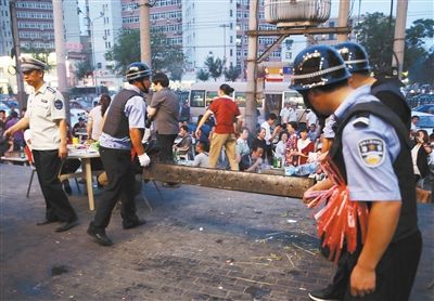 6月13日晚8點(diǎn)，朝陽(yáng)路和青年路交叉口西側(cè)，一次聯(lián)合執(zhí)法行動(dòng)中，輔警與協(xié)管抬走商戶的燒烤用具。新京報(bào)記者 尹亞飛 攝