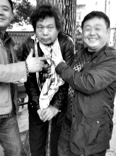 兩名接訪人員與患有癌癥的訪民段新德合影時(shí)，面帶笑容擺出勝利的手勢。