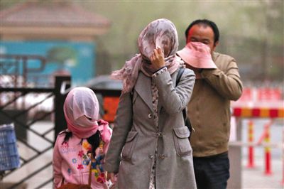 昨日下午，朝陽區(qū)豆各莊，行人將紗巾裹在頭上防沙塵。