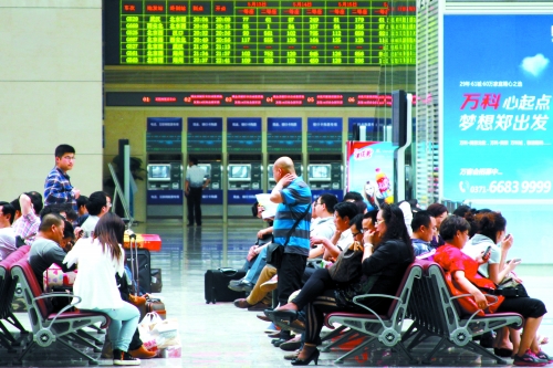 候車大廳溫度很高，一名乘客一手扇風(fēng)、一手擦汗