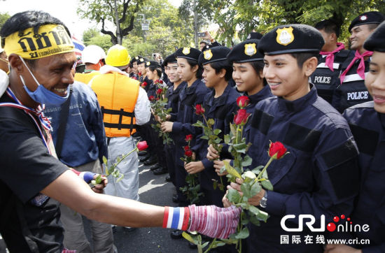 2013年12月03日,曼谷總理府與曼谷警署允許反政府示威民眾進(jìn)入,雙方進(jìn)入暫時(shí)“停戰(zhàn)”狀態(tài)迎接泰王生日。曼谷警察總署,女警們手持鮮花送給反政府示威民眾。圖片來源:Manish Swarup/東方IC