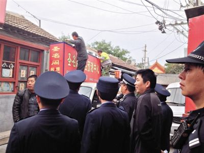 昨日下午,東城區(qū)工商、城管、公安等部門,對(duì)雍和宮附近的預(yù)測(cè)中心進(jìn)行清理整頓,站在車頂?shù)膬擅と苏鸪患摇邦A(yù)測(cè)中心”的招牌。因雍和宮、白云觀等文化景點(diǎn)外聚集大量算命先生,被媒體稱為“算命一條街”。本版攝影/新京報(bào)記者 李寧 攝