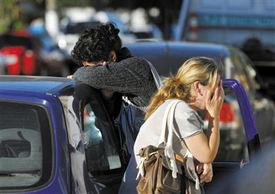 27日，遇難者親友在火災(zāi)現(xiàn)場旁哭泣。