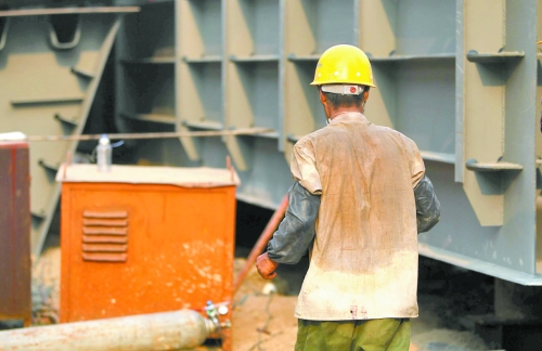 工地上，一建筑工人的衣服被汗水浸透。