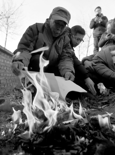 李三仁在兒子墳前焚燒再審無(wú)罪判決文書(shū)的復(fù)印件。新華社發(fā)