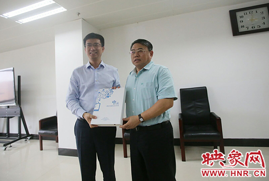 阿里云計(jì)算總裁胡曉明向河南省新聞出版廣電局局長朱夏炎遞交《中原云平臺(tái)交付手冊(cè)》。