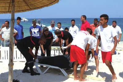 6月26日，在突尼斯蘇塞，救生員和醫(yī)務(wù)人員在發(fā)生襲擊事件的海灘運送一名死者的遺體。新華社發(fā)