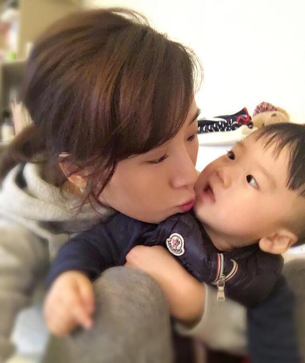 照片中李念狂吻兒子，小寶貝自顧自地玩著。