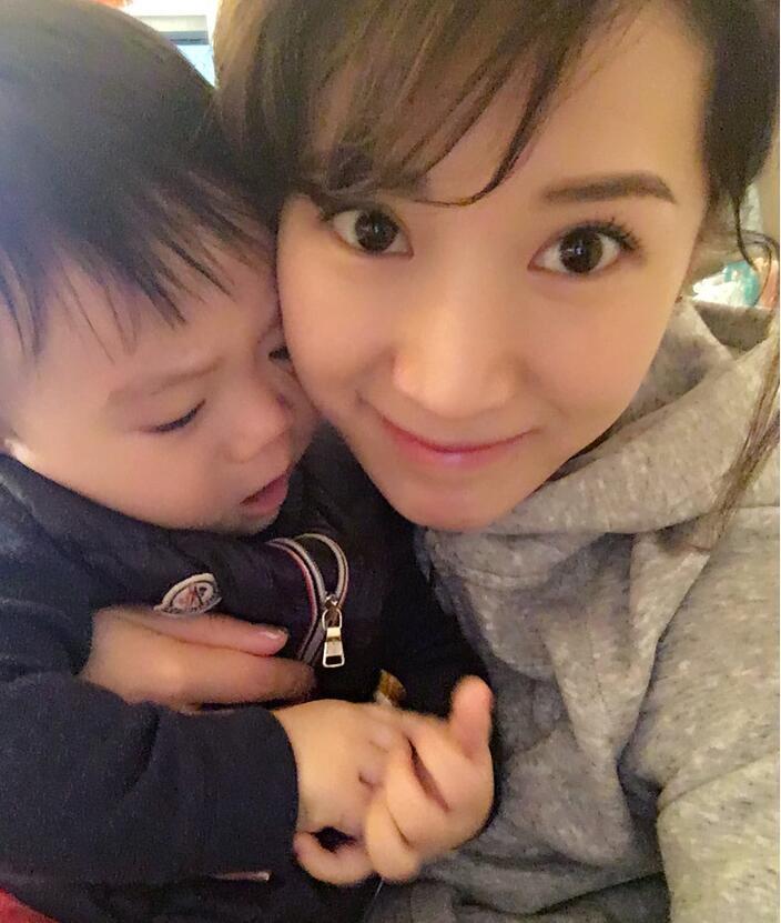 照片中李念狂吻兒子，小寶貝自顧自地玩著。