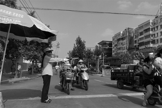 昨日，開封市區(qū)一名協(xié)管員在指揮群眾過馬路