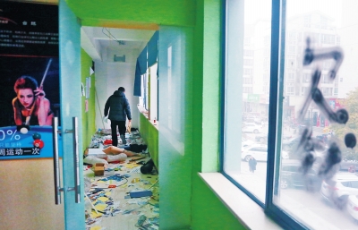 　健身會(huì)所地上一片狼藉，玻璃上噴著黑色“欠錢”二字。