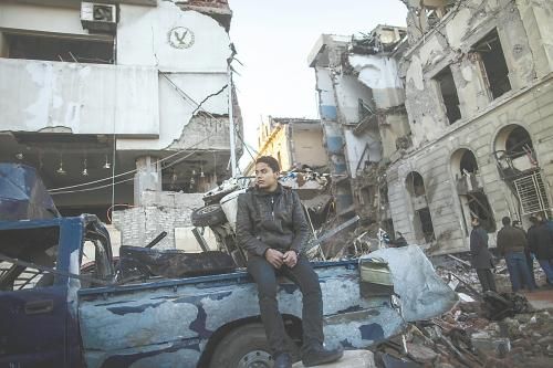 埃及曼蘇拉市警察局24日遭汽車炸彈襲擊，被疑是穆兄會的報復(fù)。圖為一名男子在被炸毀的警察局前。