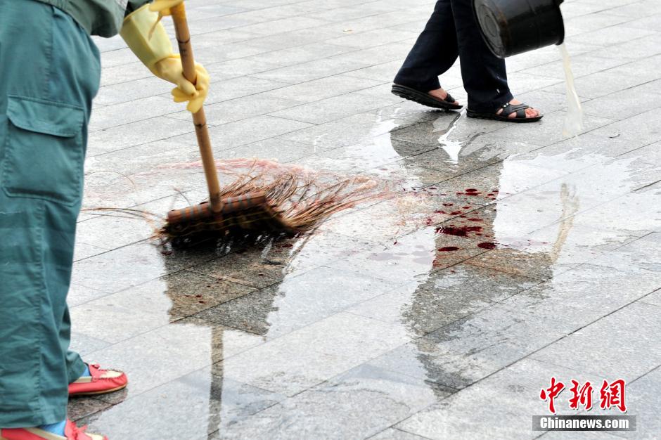 圖為環(huán)衛(wèi)工人在清理案發(fā)地點(diǎn)的血跡。