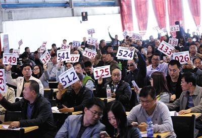 競(jìng)拍者正在練習(xí)舉牌動(dòng)作，以便拍賣時(shí)讓工作人員看清號(hào)牌。