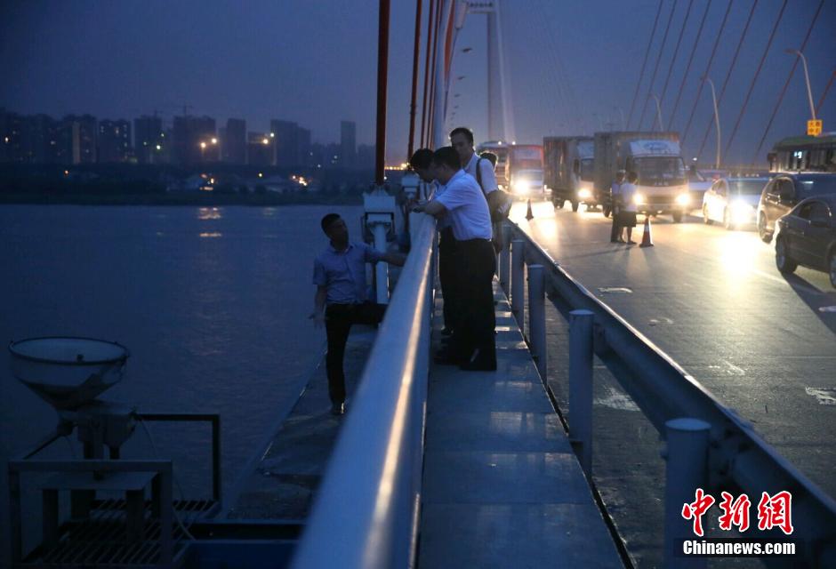 圖為武漢警方談判專家正在與翻爬至大橋外側(cè)護欄的劫持者談判。