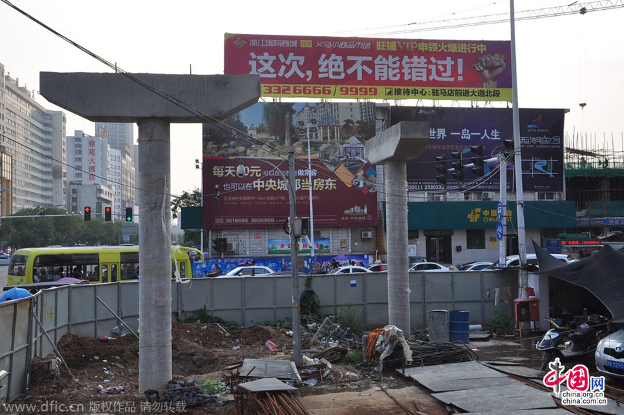 過街天橋一側(cè)的橋樁早已打好,可是對面的郵政銀行網(wǎng)點依舊在照常營業(yè)。