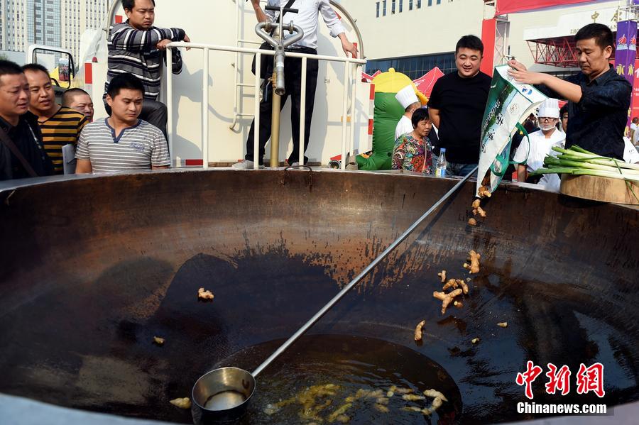 工作人員向大鍋內(nèi)加入油和姜等烹飪調(diào)料。 圖片來源：CFP視覺中國