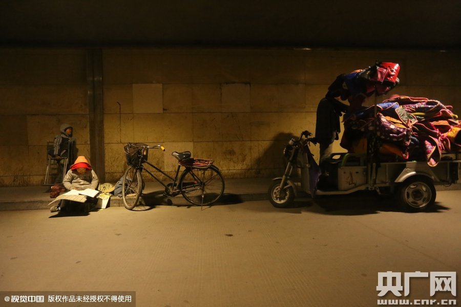 2015年11月8日晚，鄭州，7歲男孩涵洞橋下陪父母練攤，路邊燈下坐小馬扎上寫作業(yè)。