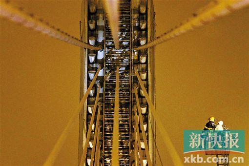 截至今日零時，男子仍未有下橋舉動。圖為公安和消防人員乘消防云梯在高空上和男子交談。