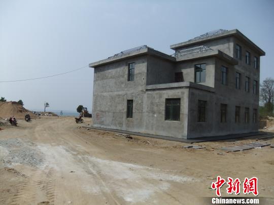 鴨河水庫庫區(qū)邊的新建別墅，一面墻上寫著“拆”，另一邊在加緊施工。吳揚　攝